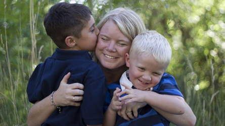 A mother hugging two sons